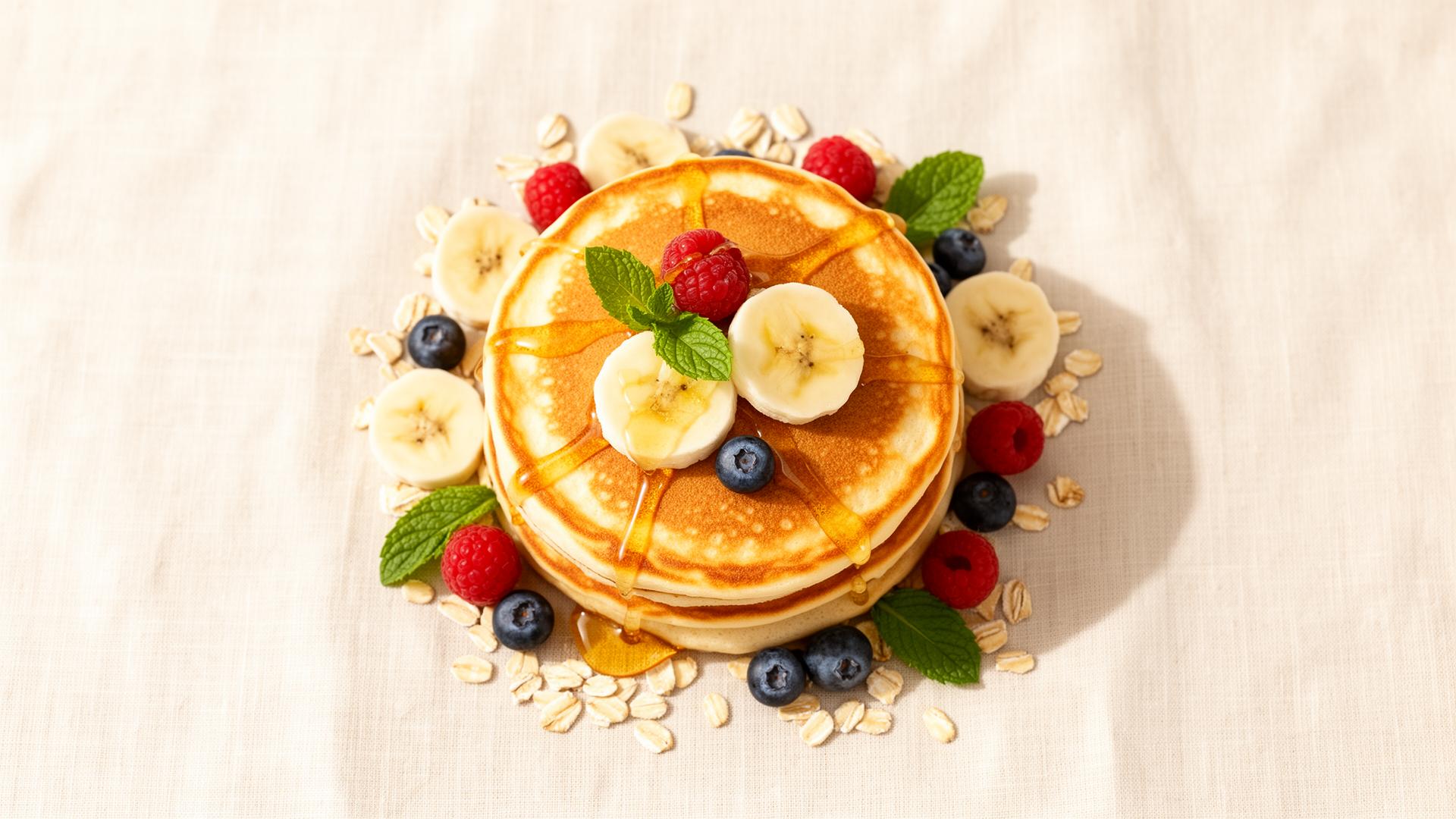 Stack of golden Nutrigra pancakes with banana, berries and oats